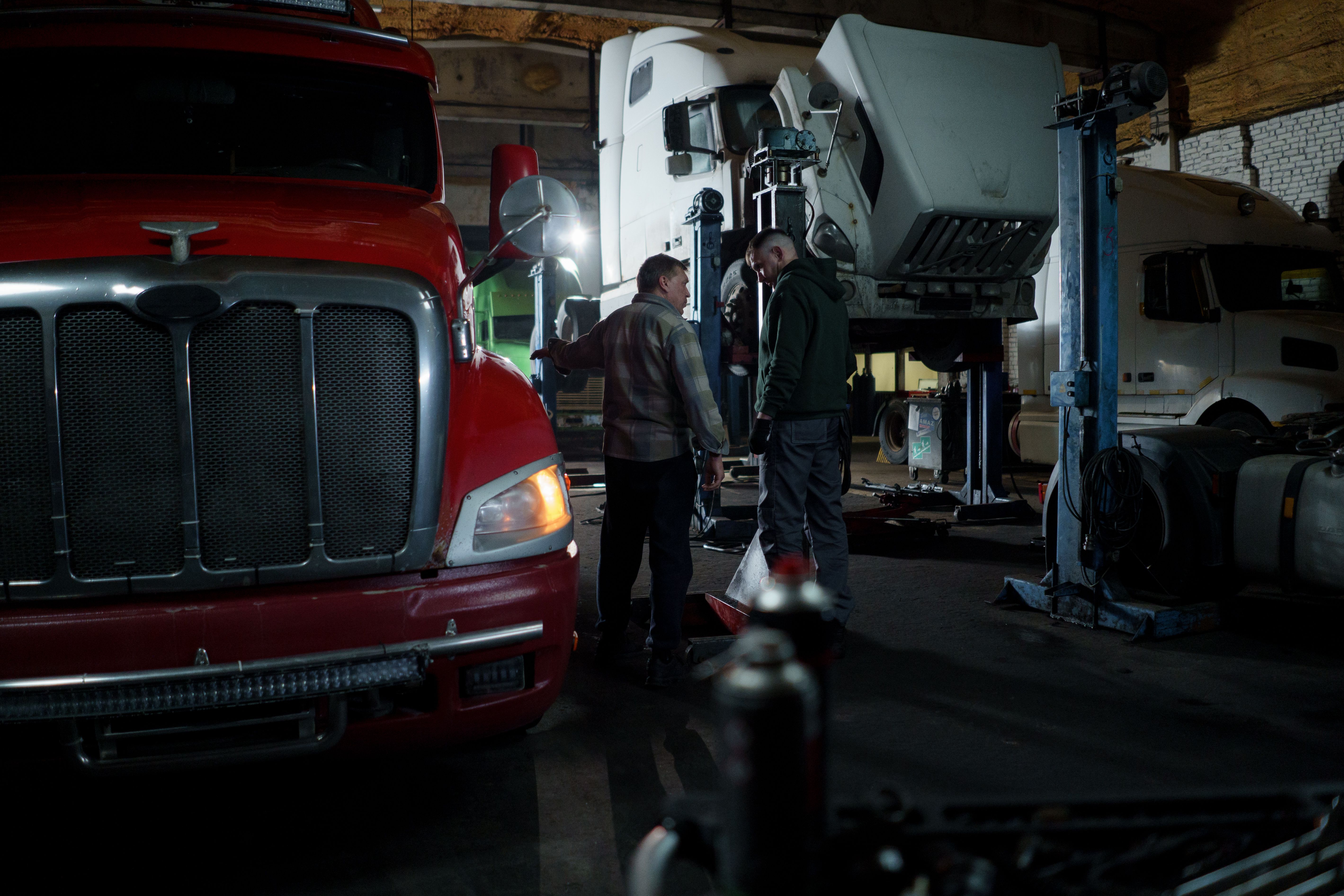 Mechanics beside commercial trucks in a repair bay