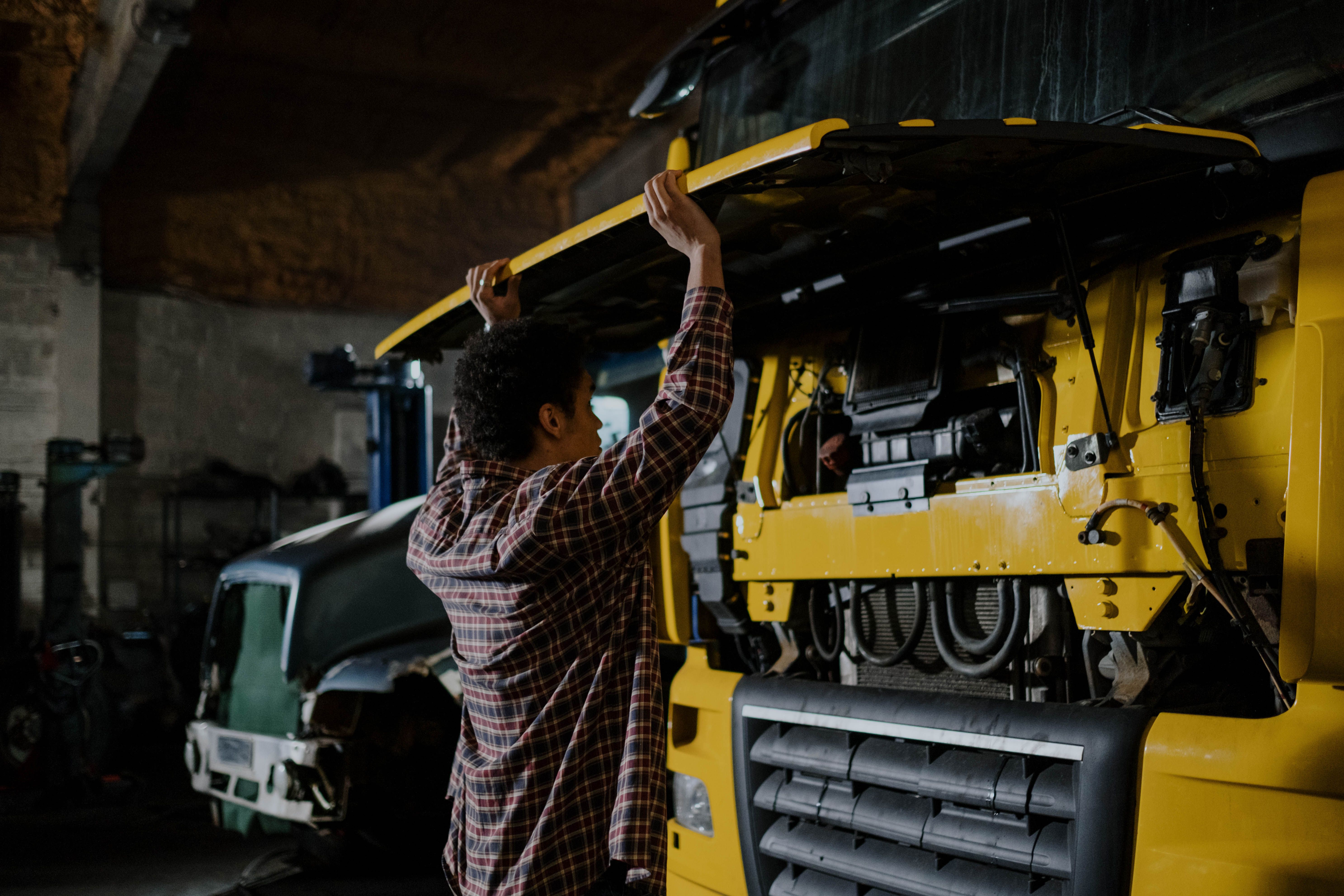Mechanic opening the front of a yellow truck for service